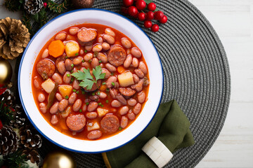 Asturian fabada with broad beans and Iberian chorizo ​​on a table decorated with Christmas motifs. Typical recipe from northern Spain.