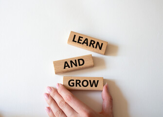 Learn and grow symbol. Concept words 'Learn and grow' on wooden blocks. Beautiful white background. Businessman hand. Business and Learn and grow concept. Copy space.