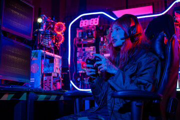 Young woman wear gaming headphones playing esports games console gaming room, Gamer using joystick...
