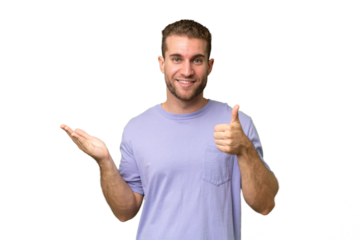 Young handsome caucasian man isolated on green chroma background holding copyspace imaginary on the palm to insert an ad and with thumbs up