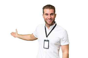 Young caucasian man with ID card isolated on green chroma background extending hands to the side for inviting to come