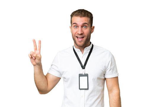 Young caucasian man with ID card isolated on green chroma background smiling and showing victory sign