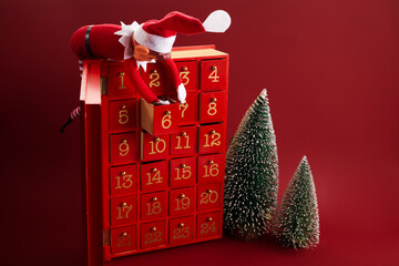 Christmas advent calendar with an elf and gifts on red background