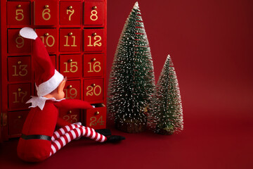 Christmas advent calendar with an elf and gifts on red background