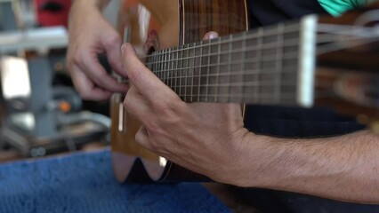 Spanish guitar maker, or luthier, playing a flamenco guitar to test its sound