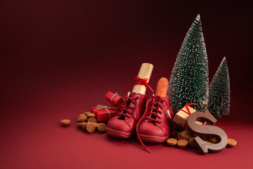 Saint Nicholas - Sinterklaas day with shoe, carrot and traditional sweets on red background