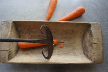 Chopping carrots with an old kitchen axe in a wooden trough