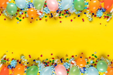 Birthday background top view. Frame of balloons and various party decorations on a yellow background