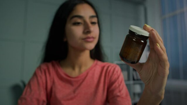 Young arabian spanish woman hold bottle with pills medication read medical prescription. Sick female patient take medicine prepare to drink painkiller drug tablets meds for abortion or health immunity