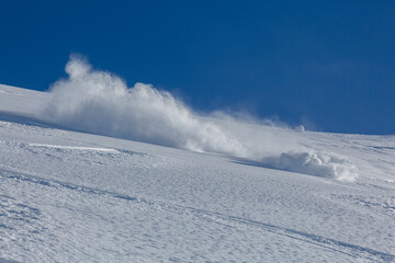 freeride snowboarder goes downhill and brakes spraying loose deep snow. Adrenaline outdoor winter adventures