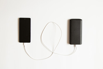 A portable rechargeable battery and a smartphone lie on a white background