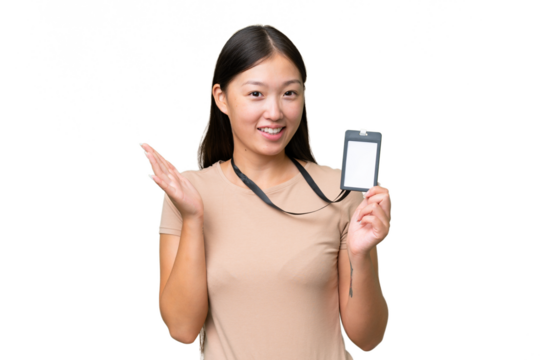 Young Asian woman with ID card over isolated background saluting with hand with happy expression