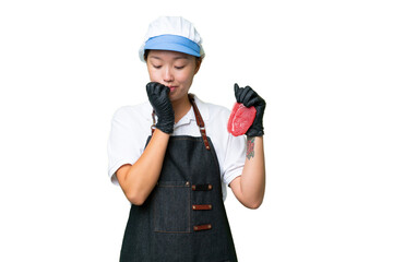 Young caucasian woman wearing an apron and serving fresh cut meat over isolated background having doubts