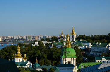 Fototapeta na wymiar Coupolas of Kyiv Pechersk Lavra Monastery, Paton bridge, and modern residential buildings at the left bank of rhe Dnipro river at the capital of Ukraine 