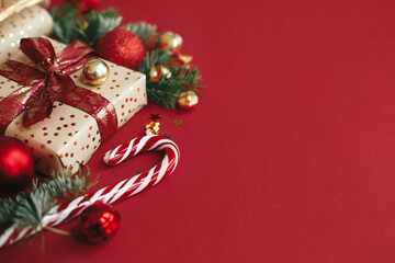 Modern christmas composition. Stylish christmas gift, wrapping paper,  fir branches, candy cane and...