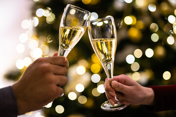 Crop close up of man and woman hold glasses with champagne clink greet congratulate with New Year. Couple celebrate Christmas winter holidays at home together, wish luck and joy. Celebration concept.