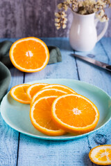 Round slices of fresh orange on a plate on the table. Vitamin antioxidant diet. Vertical view