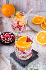 Hard seltzer cocktail with berries, orange, rosemary and ice in glasses on the table. Vertical view