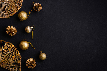 Christmas flat lay background with golden holiday decorations. Top view on black with copy space.
