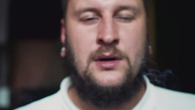 Cool slow-motion shots of smoke exhaling directly into the camera. Shooting in slow motion of a bearded smoker
