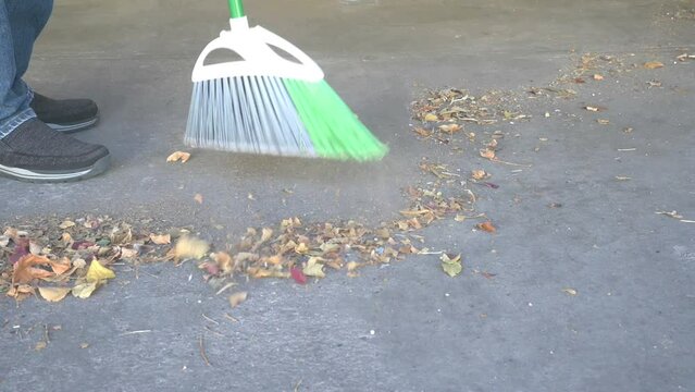 Broom sweeping a garage floor of leaves.