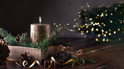 Golden advent candle on wooden box with christmas lights. Dark photo. Copy space