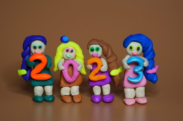 Figurines of girls made of plasticine and the figure 2023. A festive event. Calendar date.