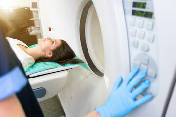 CT scan technologist overlooking patient in Computed Tomography scanner during preparation for...