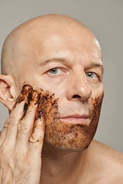 Adult man using organic coffee scrub on his face exfoliating dead skin