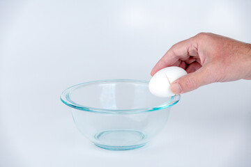 Farm fresh egg cracked on the edge of a glass bowl