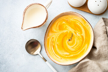 Pumpkin soup with cream in the craft bowl at stone table. Healthy eating. Top view with copy space.