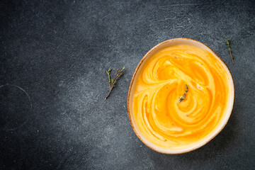 Pumpkin soup with cream at black stone table. Healthy eating. Top view with copy space.
