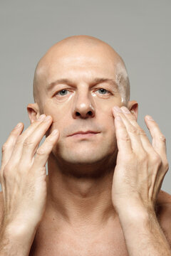 Vertical portrait of adult man using anti-age collagen under eye patches