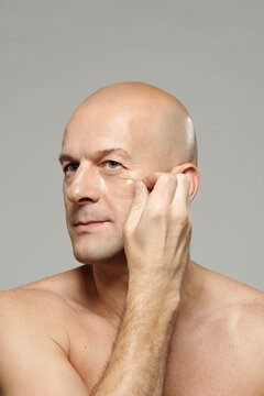 Beauty portrait of attractive mature male model applying collagen patches under his eyes
