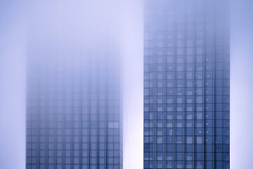 Fototapeta na wymiar Windows of skyscrapers in the fog, background copy space. Metal structures with windows of a high-rise building in smog, close-up