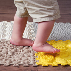 Baby toddler foots close-up on a medical orthopedic mat. Child legs with flat feet on a medical...