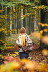 Woman with backpack hiking in autumn forest