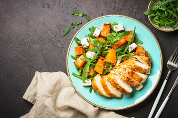 Warm salad with baked chicken breast, pumpkin, blue cheese and arugula. Dash diet, keto diet meal. Top view with copy space.