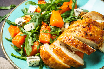 Warm salad with baked chicken breast, pumpkin, blue cheese and arugula. Healthy diet food.
