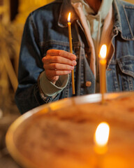 woman in the temple puts candles and prays. religion and spiritual growth. the search for truth and mental health. a woman holds a church burning candle in her hands. prayer purification and