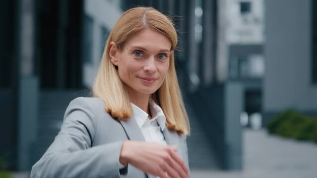 Close-up caucasian businesswoman standing in outdoors on city HR manager invites candidate for position waving hand makes come here beckoning gesture welcome business woman goes away blurred back view