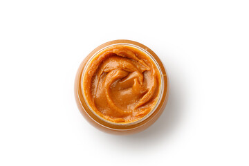 Liquid melted caramel syrup, paste in round glass jar iaolated on a white background. Curl, wave of...