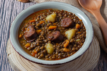 Traditional lentil soup with potatoes, carrots and chorizo sausage on a wood fire. Mediterranean cuisine 