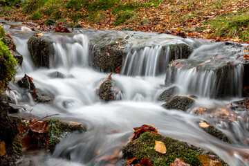 Fototapeta na wymiar Long exposure of a waterfall flowing into the Weir Water river at Robbers Bridge in Exmoor National Park