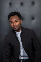young businessman in his twenties head shot on black background vertical man luxury lounge studio...