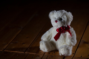 Lonely teddy bear sitting down alone in living room at night. Lonely concept, forgotten toy, international missing children's day.