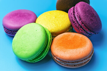 close-up of multicolored macaroons lying on colored background, French biscuit dessert made of almonds, festive almond cookie design