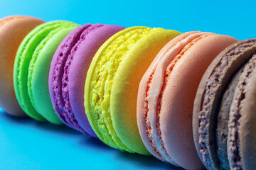 close-up of assortment of multicolored traditional French macaroons on colored background, festive almond cookie design