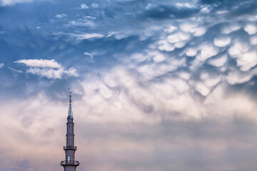 tower of Muslim mosque with crescent moon on the spire on the background of stormy epic gloomy clouds