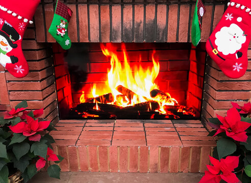 A fake fireplace is a Christmas decoration. Christmas socks, poinsettia. And the burning fire on the plasma screen is like a real fire